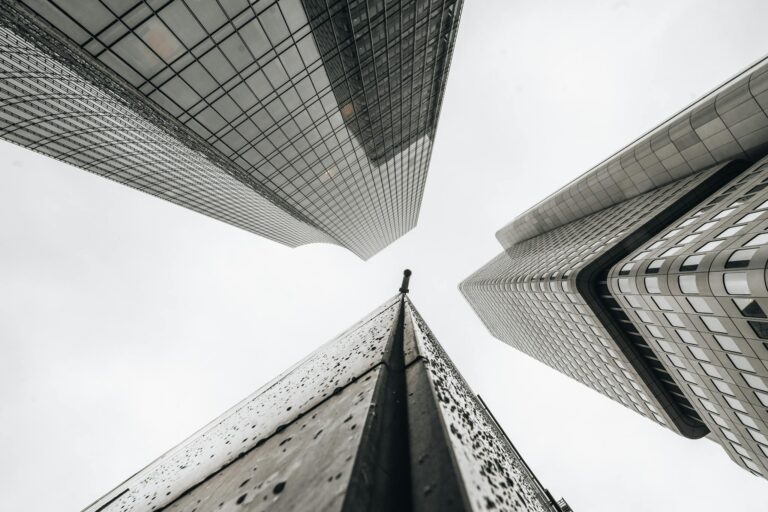 Architectural perspective of towering skyscrapers against a cloudy sky in a city environment.